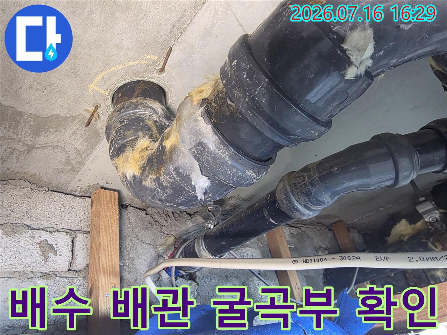 어두운 천장 안쪽에서 누수가 의심되는 배출용 배관의 연결 부위를 세밀하게 조사하는 모습입니다.