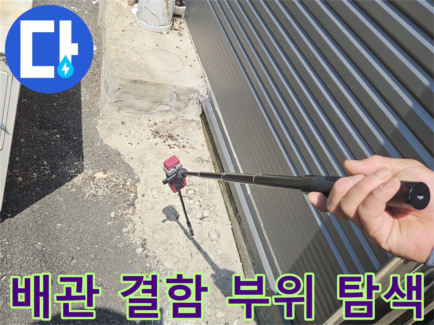 누수 의심 지점-탐지봉을 이용해 맨홀 인근 파손 부위를 가리킴