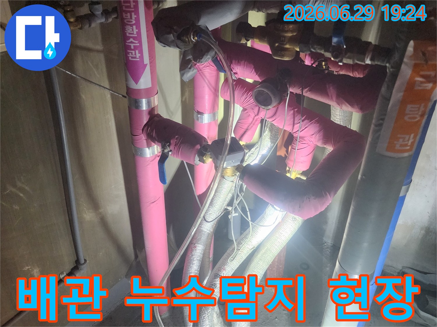 분홍색과 회색 단열재로 덮인-배관들이 복잡하게 얽혀있고-압력 게이지가 연결된-누수 테스트 현장입니다