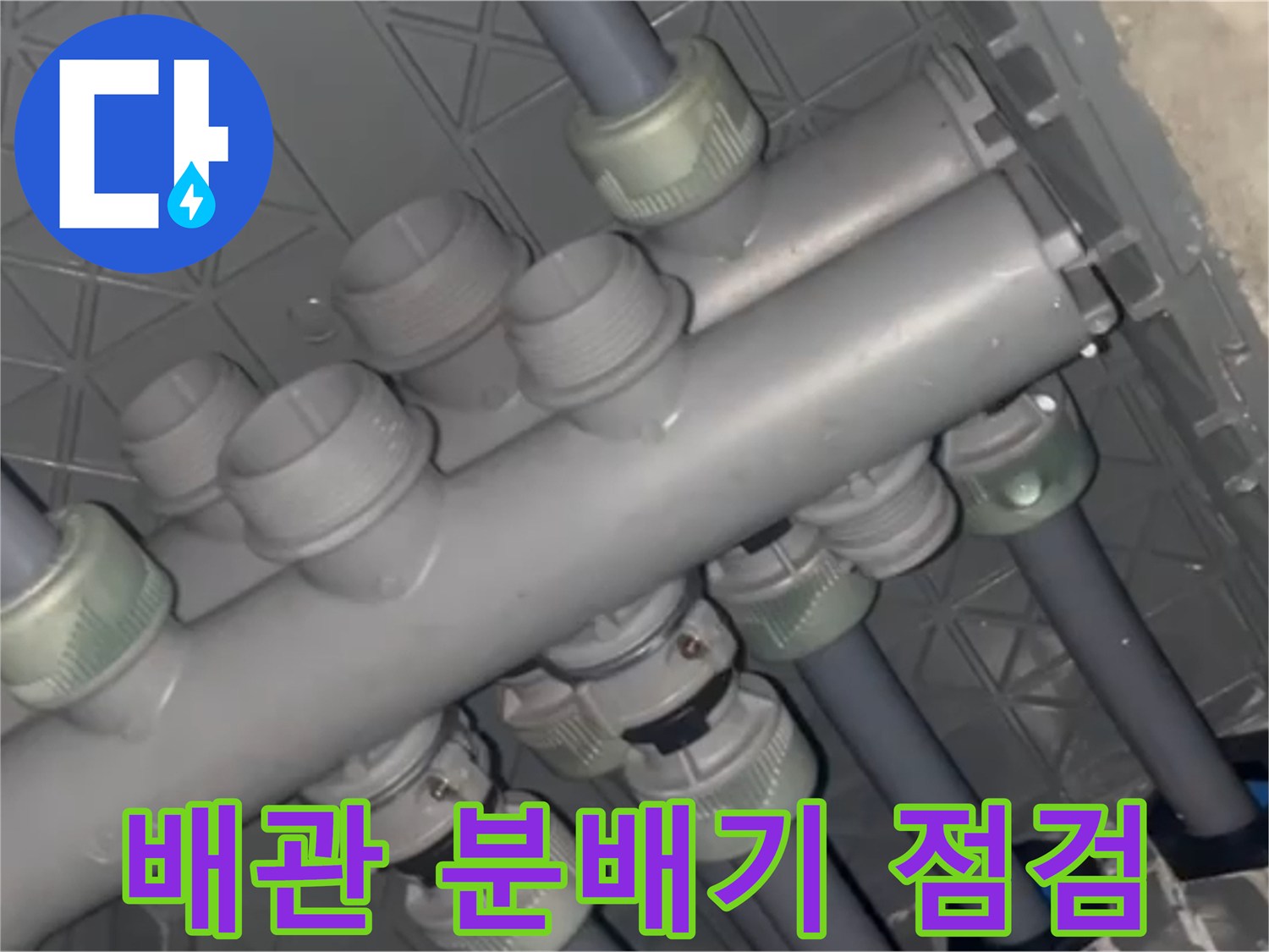 화장실 천장 하부에 노출된 회색 배관 분배기 구조물입니다.