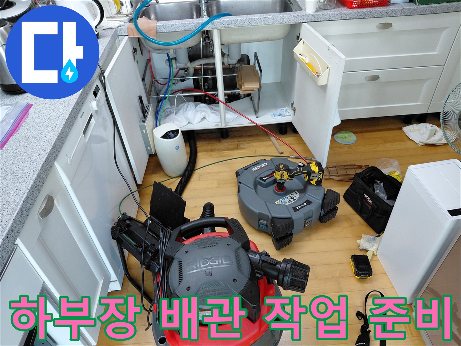 싱크대 하부장 아래 배치된 석션 장비와 청소 도구들