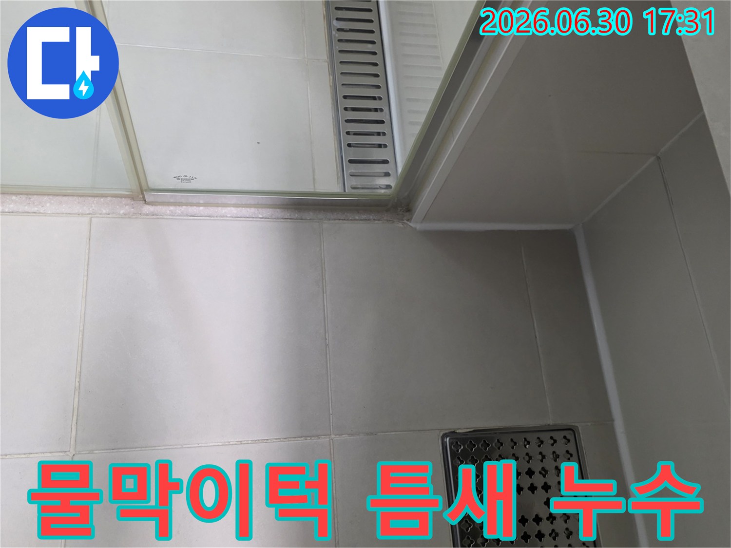 샤워부스 물막이턱 주변의 틈새에서-누수가 발생하여 변색된 부분을 보여주는 사진