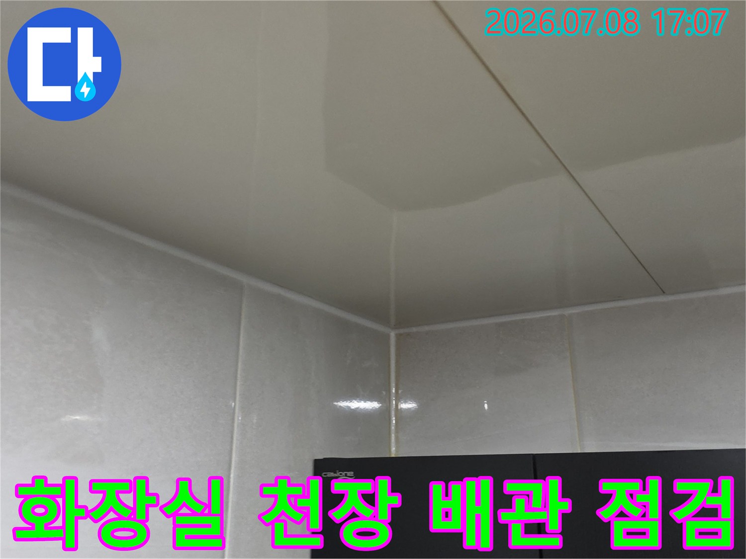 화장실 천장 안쪽의 하얀색 마감재와 배관 연결 부위를 점검하는 모습