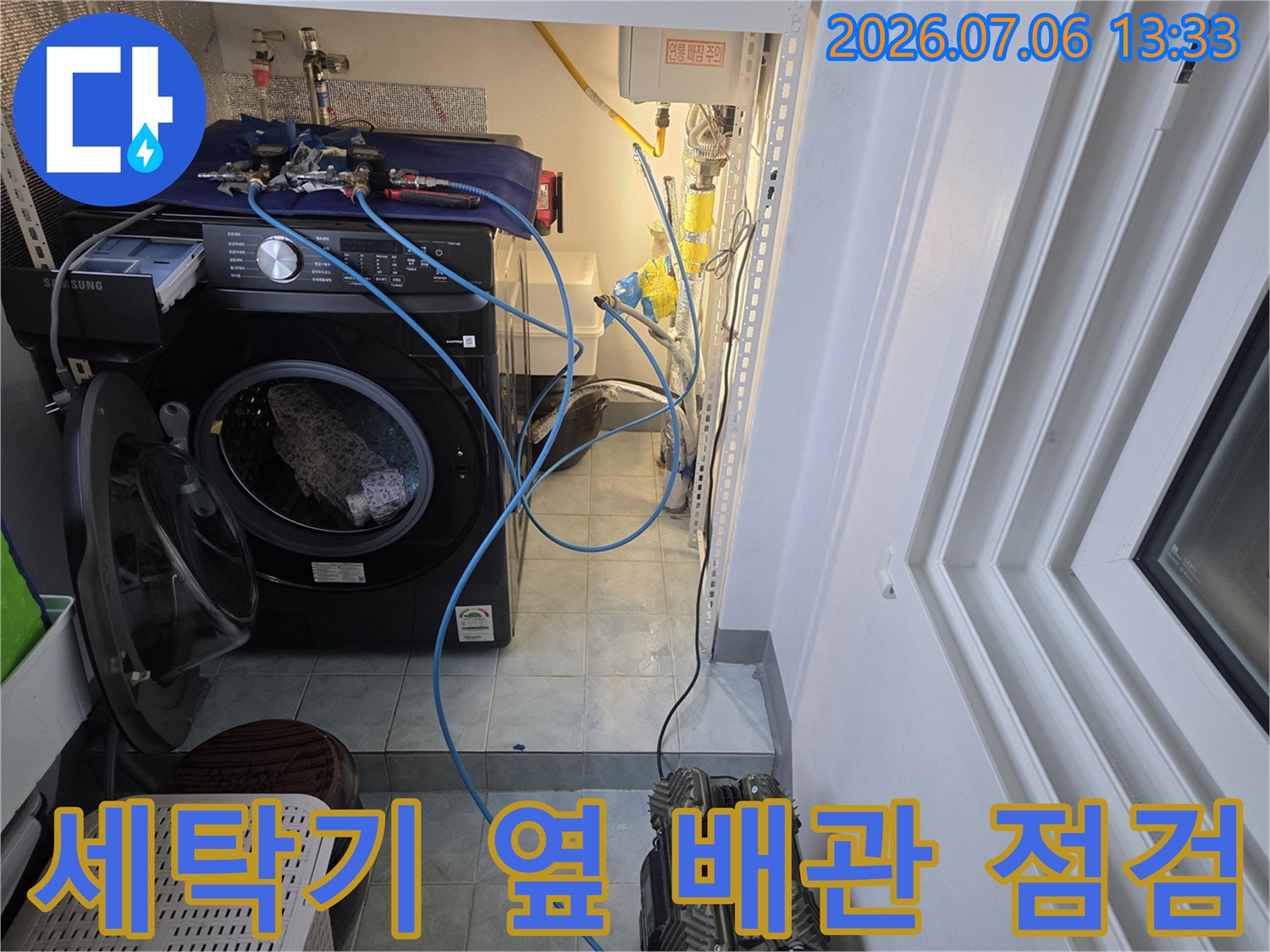 세탁기가 설치된 공간의 수도 배관과 연결 부위를 점검하는 모습