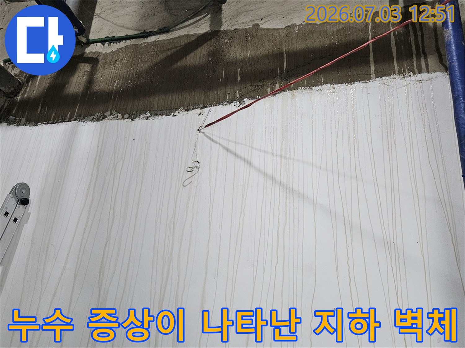 사다리가 놓여 있는 지하 공간-벽면에 물 흘러내린 자국과 파란 배관들