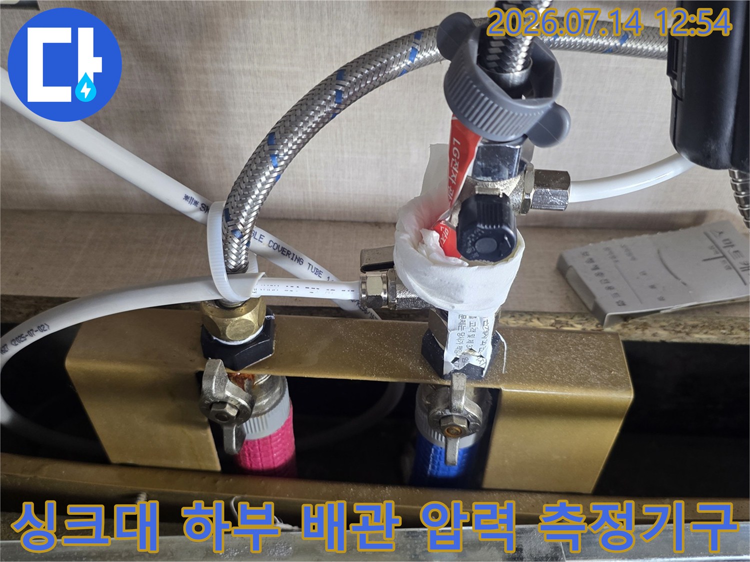 전문 게이지를 싱크대 아래 노출된 배관에 연결하여 누수 여부를 판별하는 장면