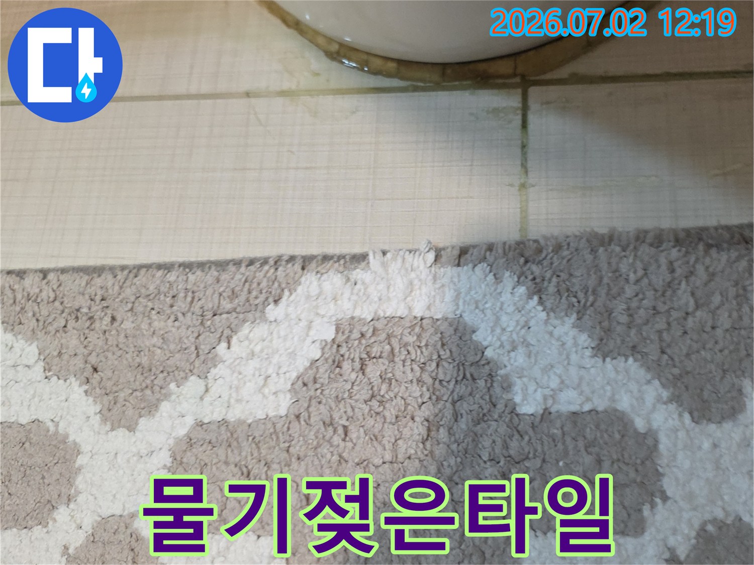 이 이미지는-변기 하단부에서-타일 틈새로-물이 새어 나온-누수 흔적을-보여줍니다.