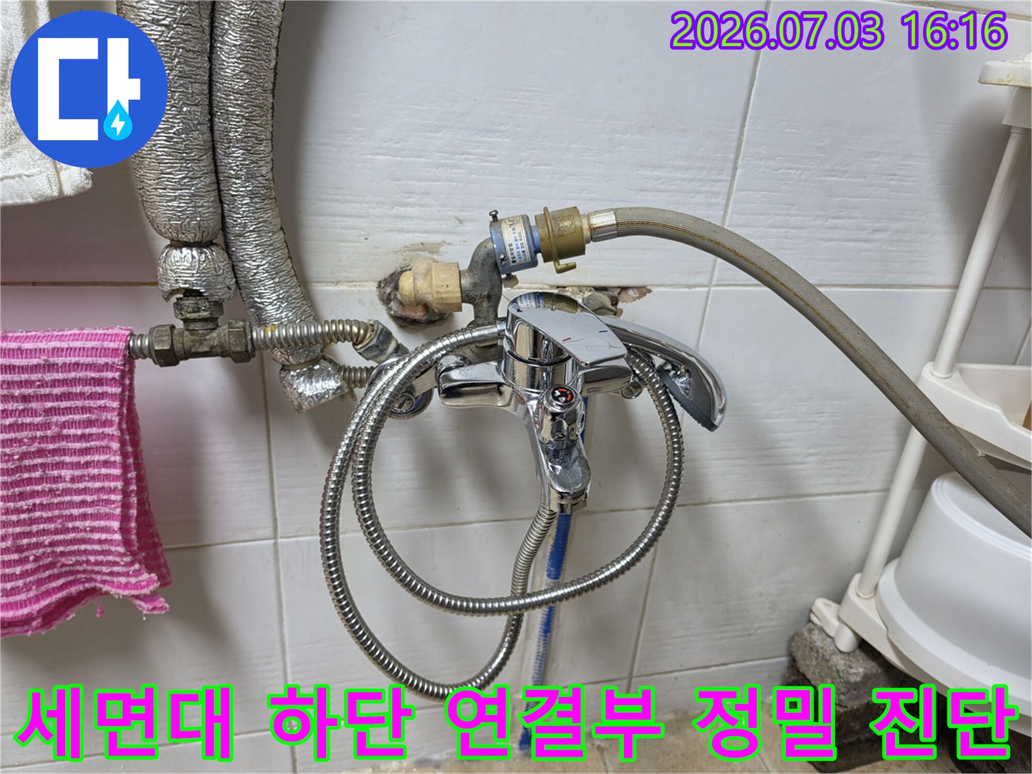 금속 소재의 세면대 호스와 벽면 배관 결합 상태를 상세하게 촬영한 모습