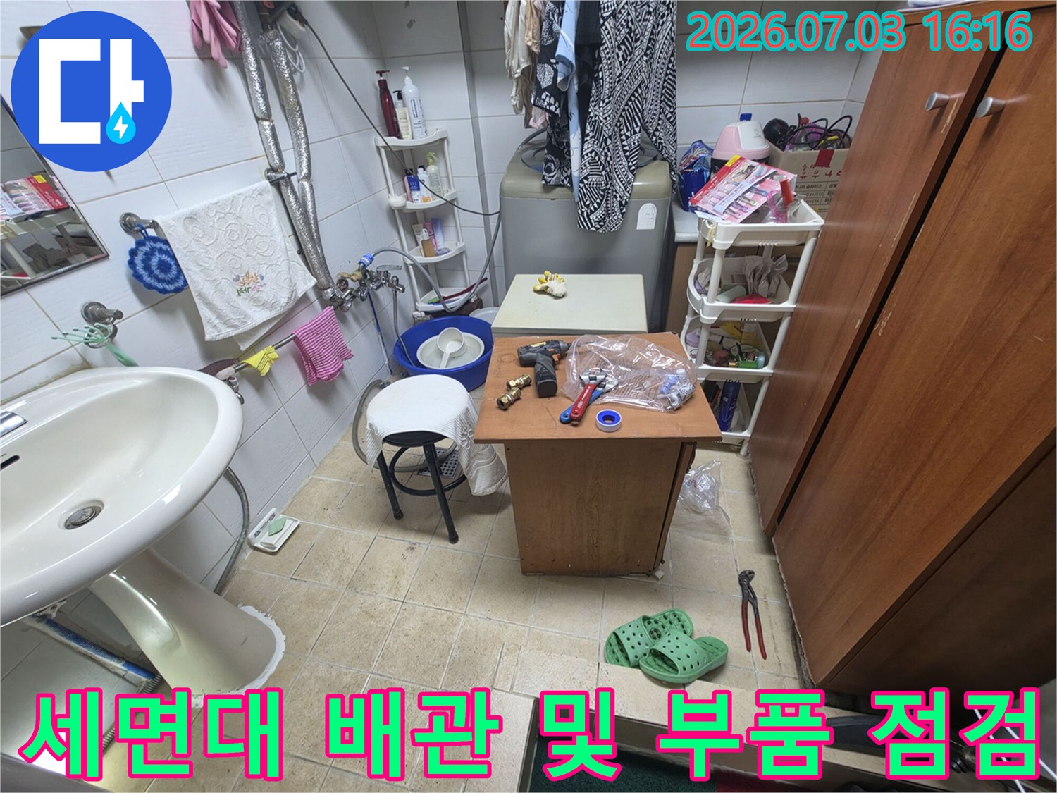 작업용 도구와 세면대 하부 노출된 여러 배관들의 모습