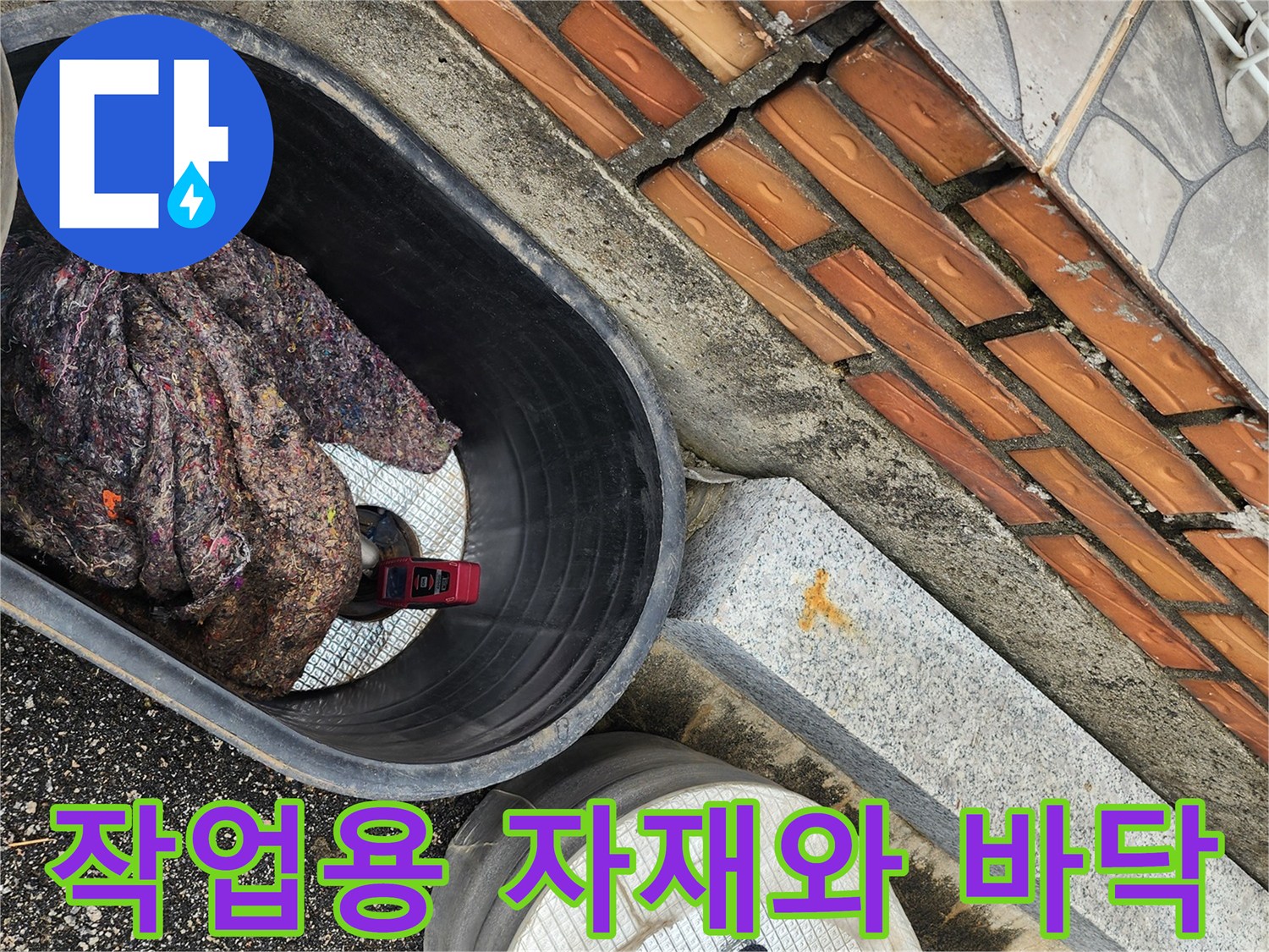 누수 지점 근처에 놓인 작업 도구와 젖은 걸레