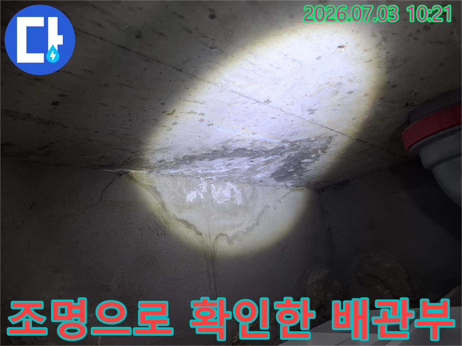 강력한 조사등을 사용하여 천장 안쪽의 누수 부위를 구체적으로 조명한 장면