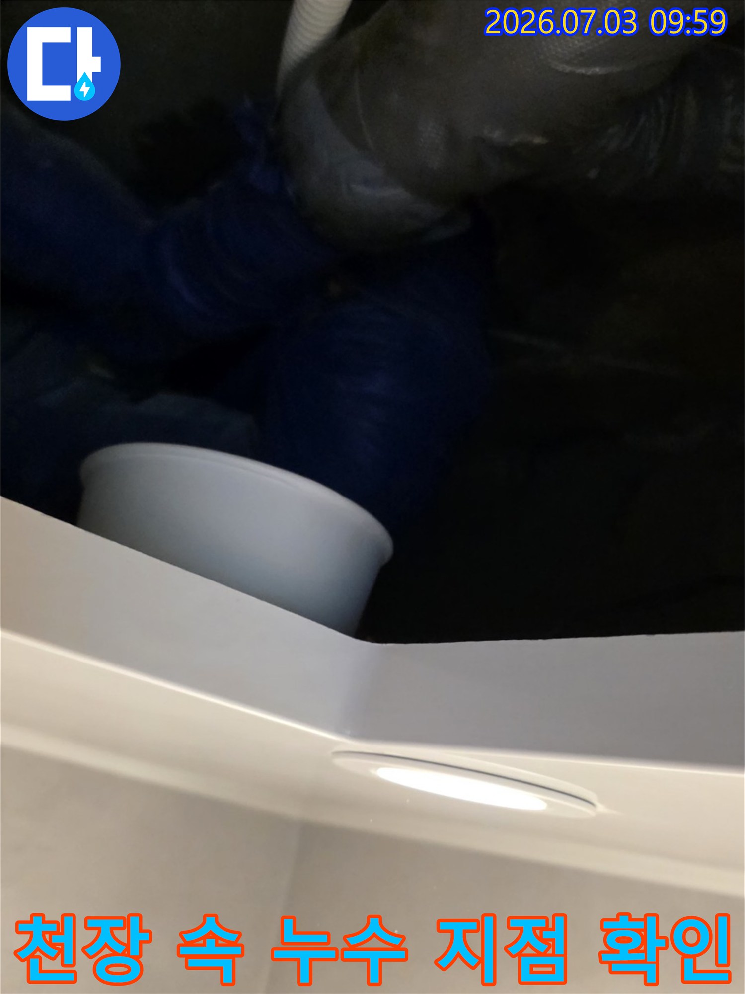 천장 점검구 안쪽 배관과 연결 부위의 누수 여부를 육안으로 검사하는 장면
