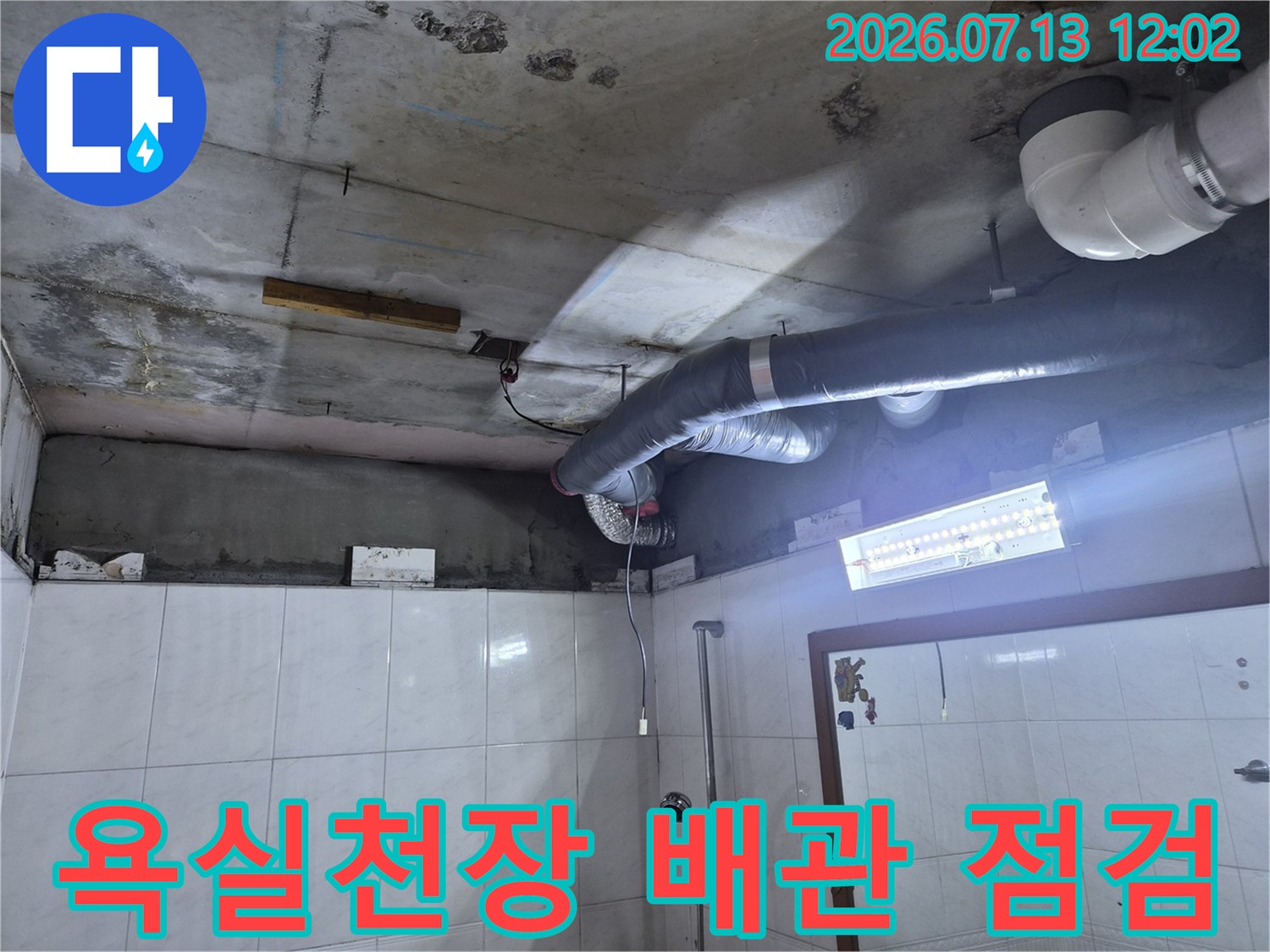 노출된 욕실 천장 내부의 배관 시스템과 콘크리트 슬래브 상태를 확인하는 모습