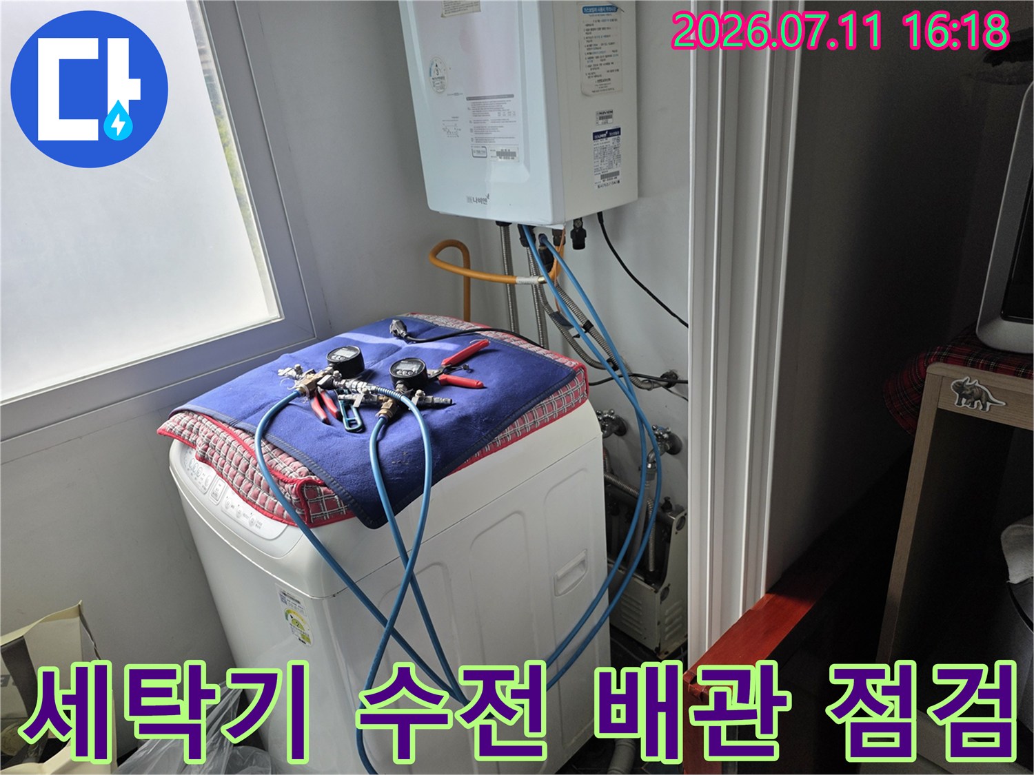 세탁기 위에 놓인 파란색 천과 연결된 노출 배관 라인