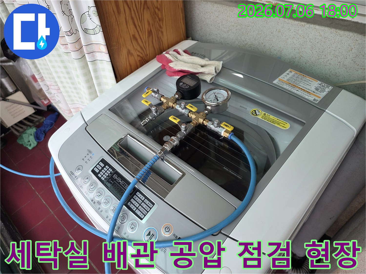 세탁기 위 노출 배관에 연결된 압력계와 호스를 통해 누수 여부를 정밀 확인하는 과정