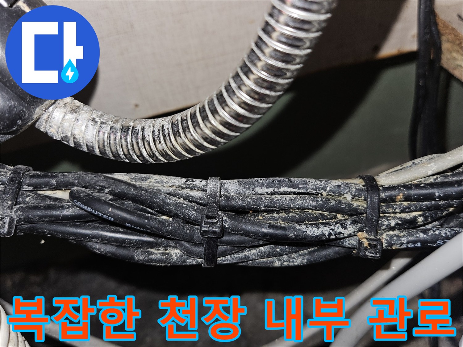 금속 주름관과 검은색 전기 케이블이 모여 있는 천장 내부