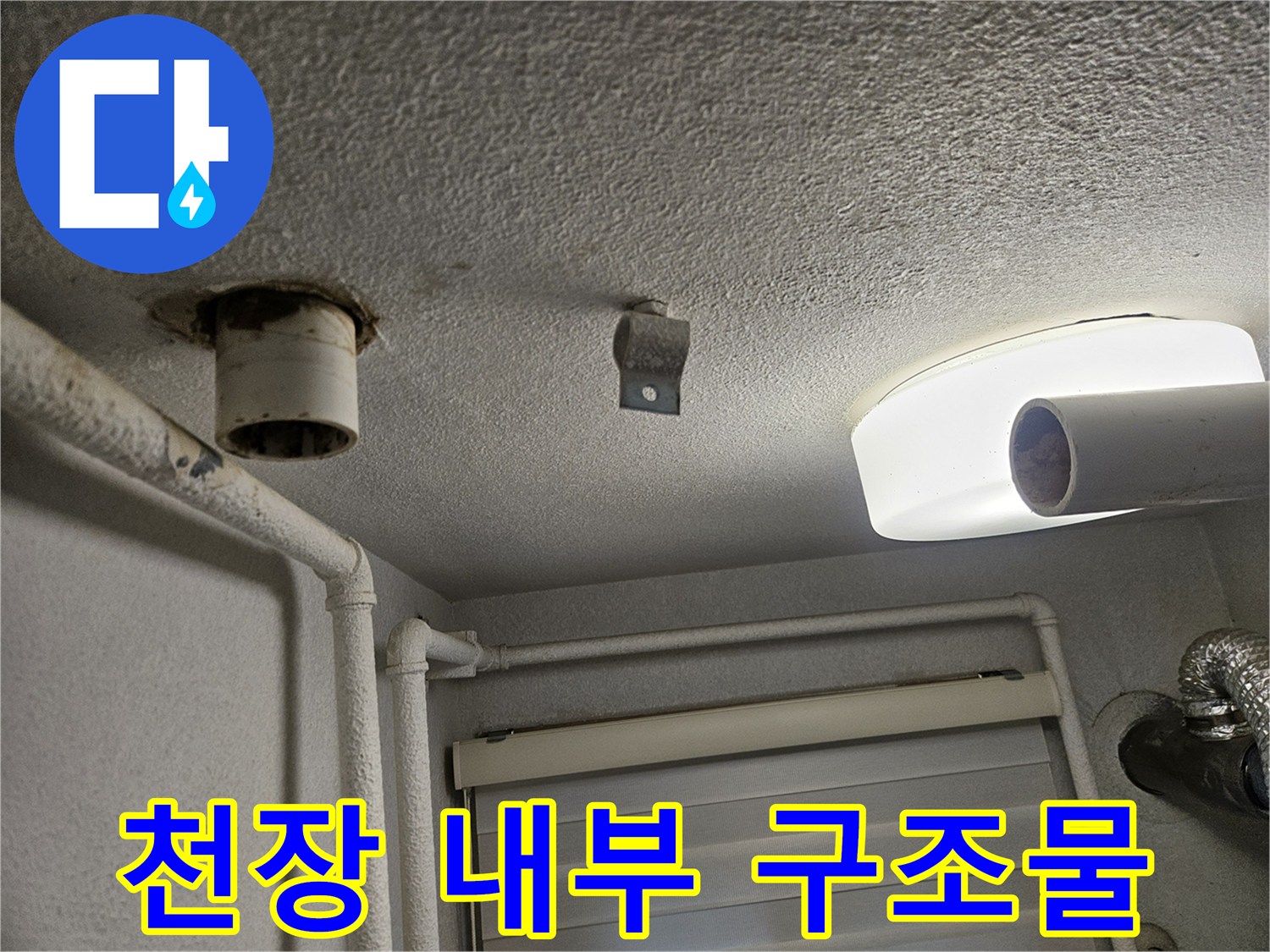 화장실 천장의 조명과 노출된 배관 부위를 촬영한 사진입니다.
