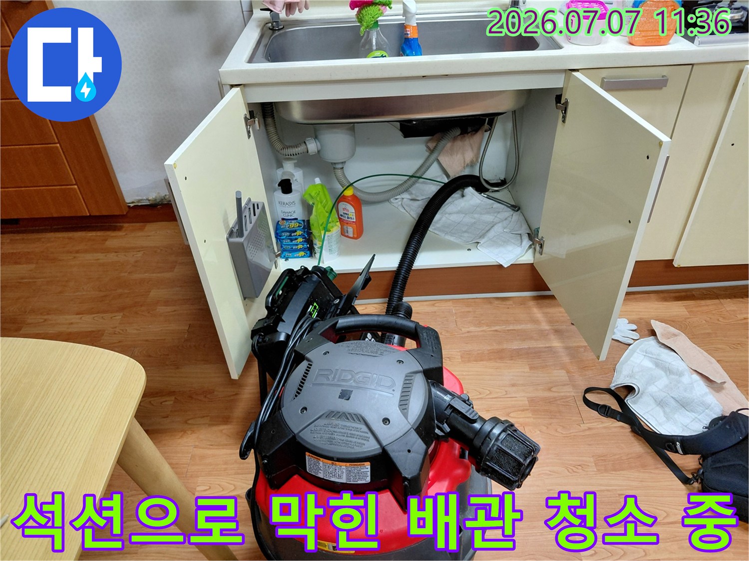 싱크대 하단부에 석션 장비를 연결하여 배관을 소통시키는 장면