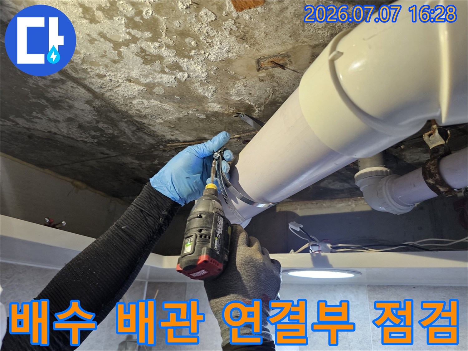 천장 배관 부속을 도구로 조절하며 누수 지점을 파악하는 장면입니다.