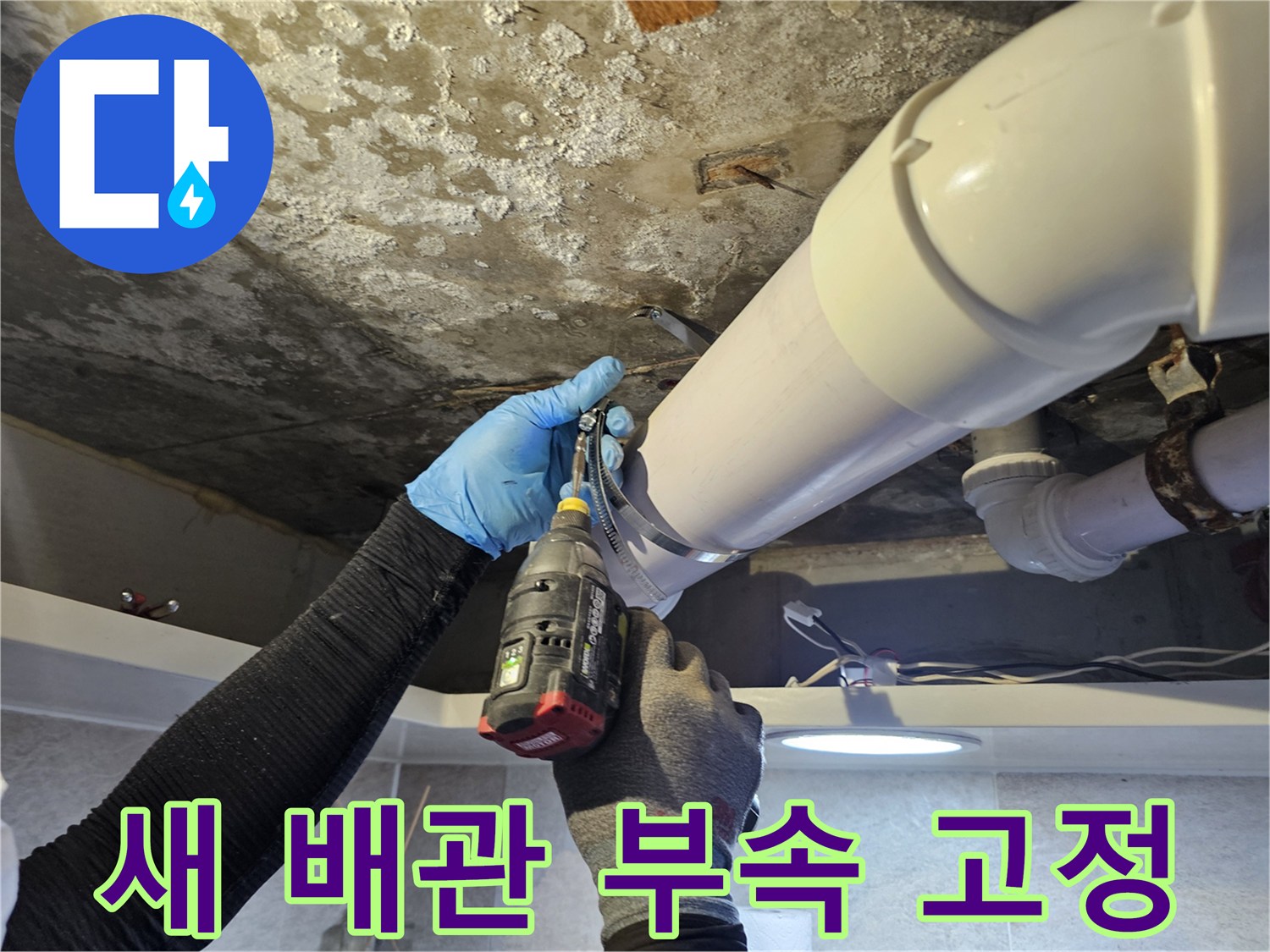 천장 배관 수리-전동 드릴로 배관 연결 부위를 조이는 모습