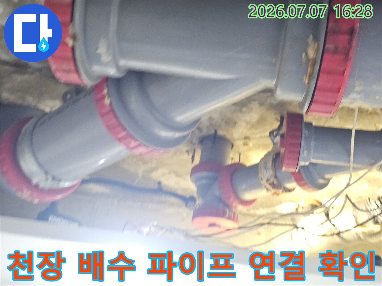 회색 배출용 파이프와 빨간 테두리 커넥터로 구성된 천장 내부 배관 구조
