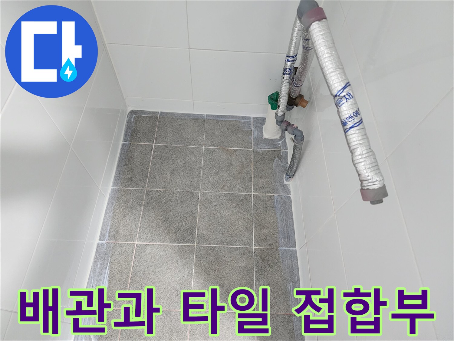 회색 타일 바닥에 연결된 은색 보온재 배관의 클로즈업