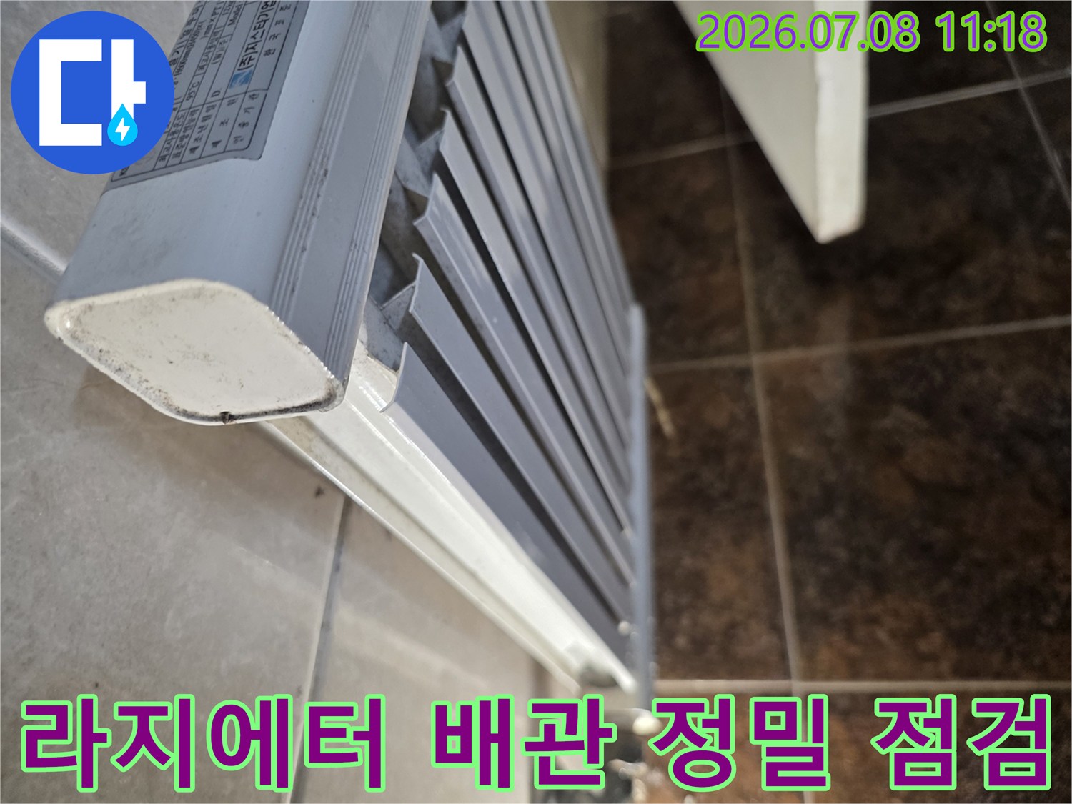 화장실의 라지에터 배관 연결 부위를 세부적으로 확인하는 공사 현장 사진입니다.