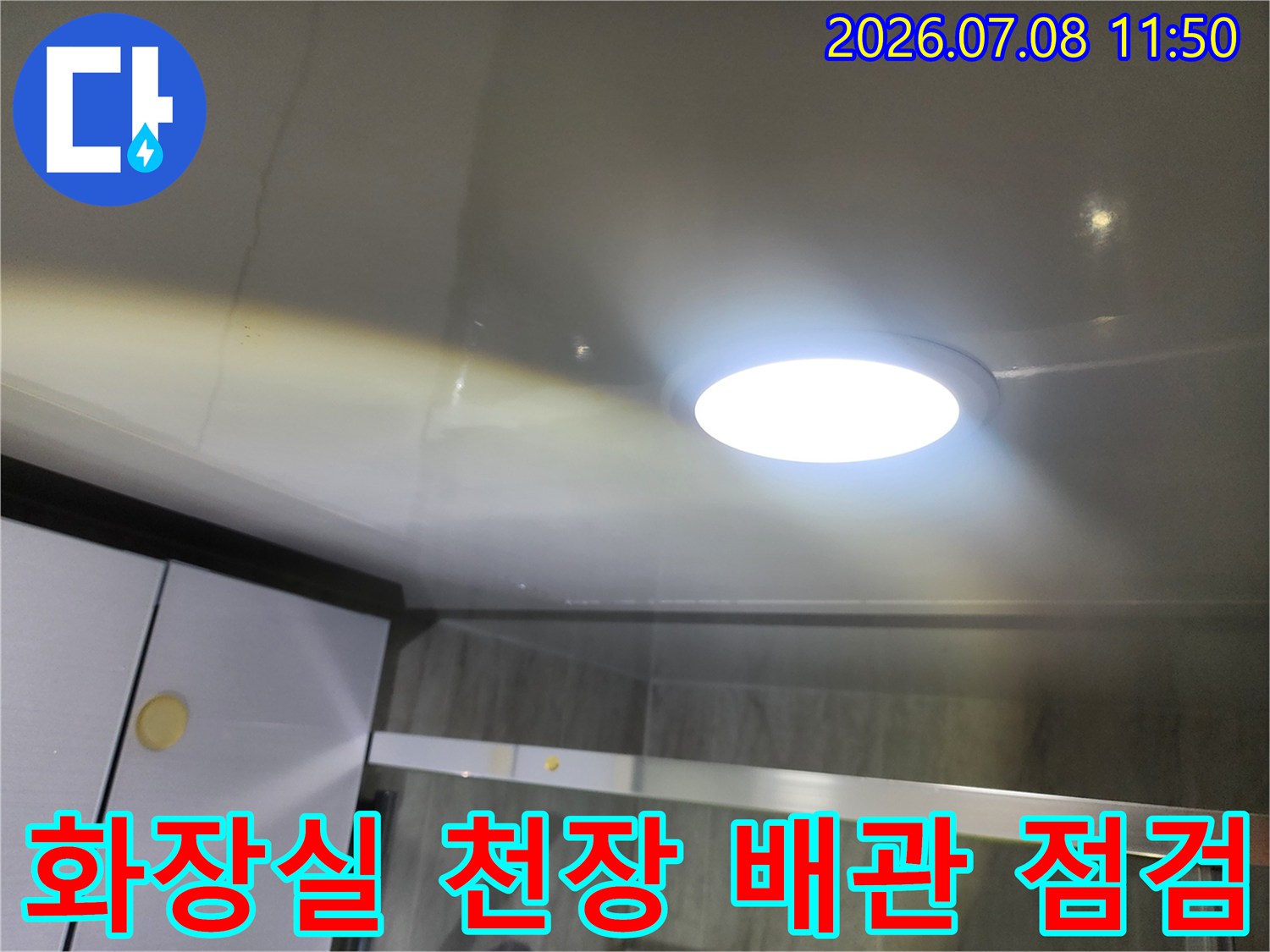 화장실 천장 내부에 설치된 조명과 배관 구조를 점검하는 모습
