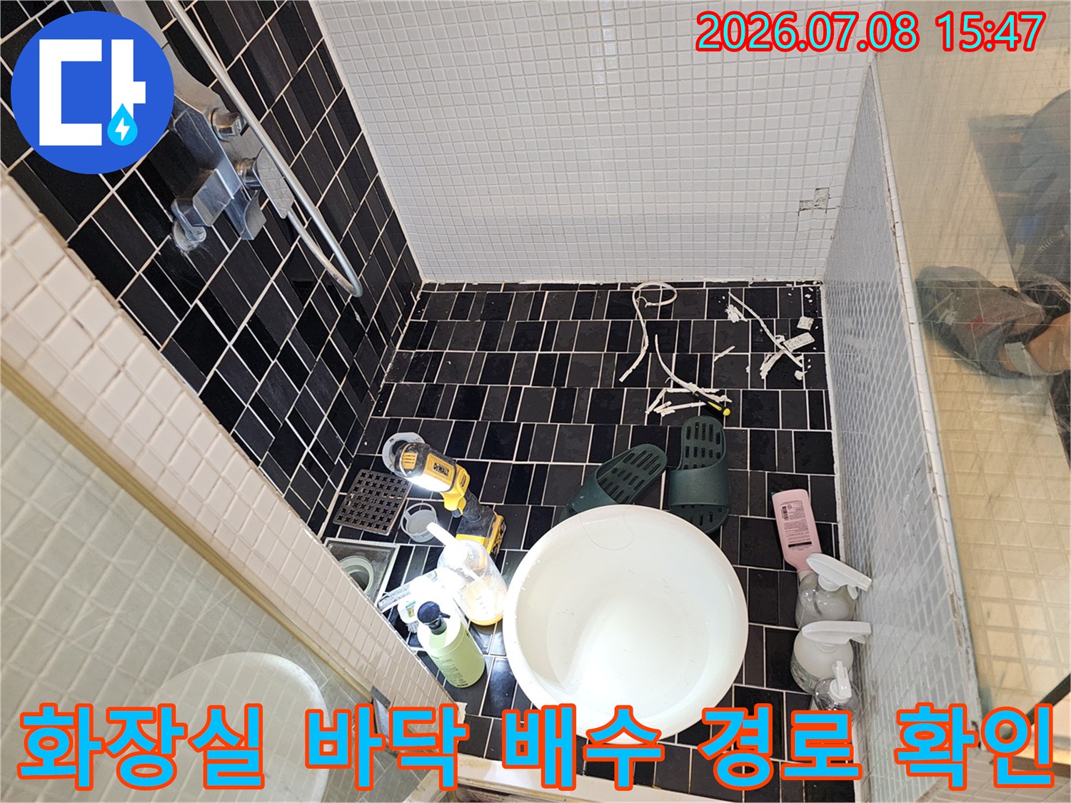 욕실 내부의 배수 시스템과 타일 마감 상태를 꼼꼼하게 점검하는 모습
