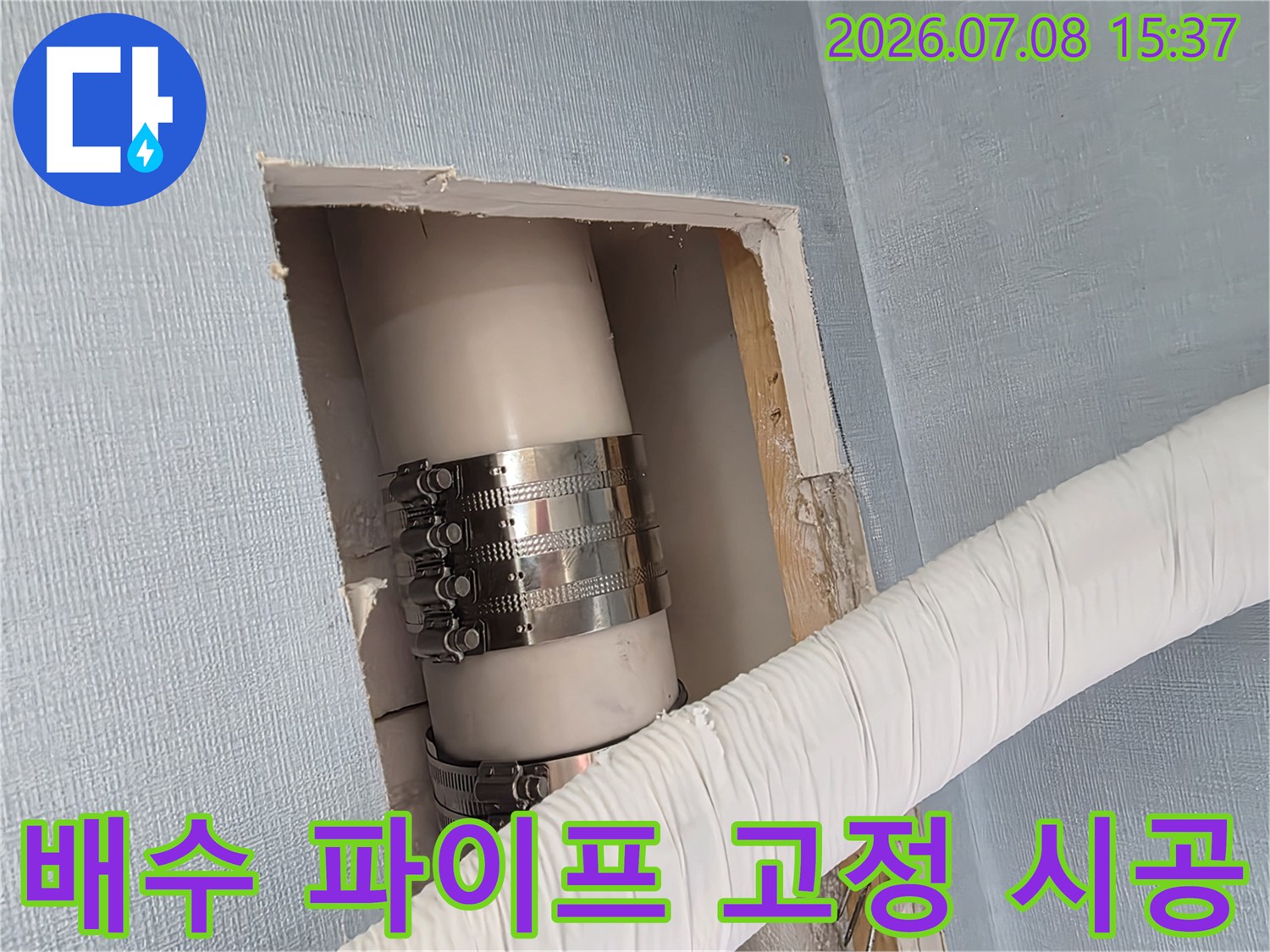 금속 클램프로 체결된 배관과 하얀색 덮개가 씌워진 외부 연결부의 모습