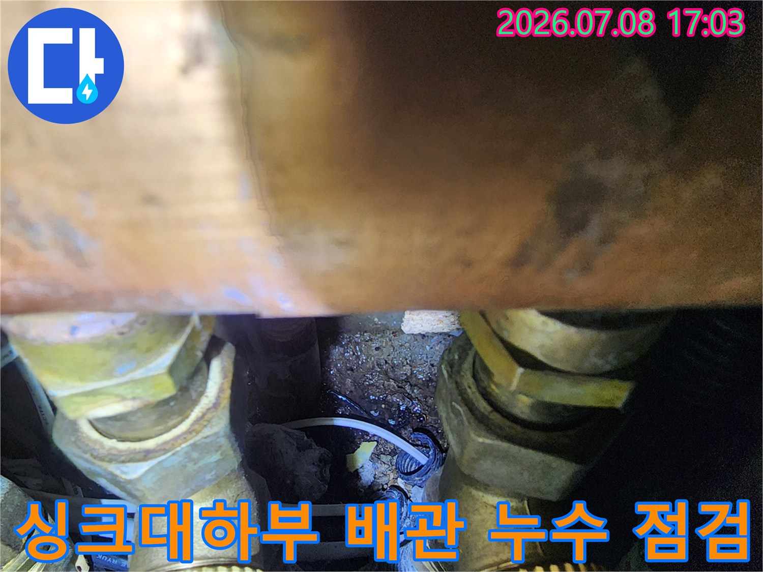 싱크대 하단 좁은 공간 속의 노출된 수도 배관과 연결 부위 촬영