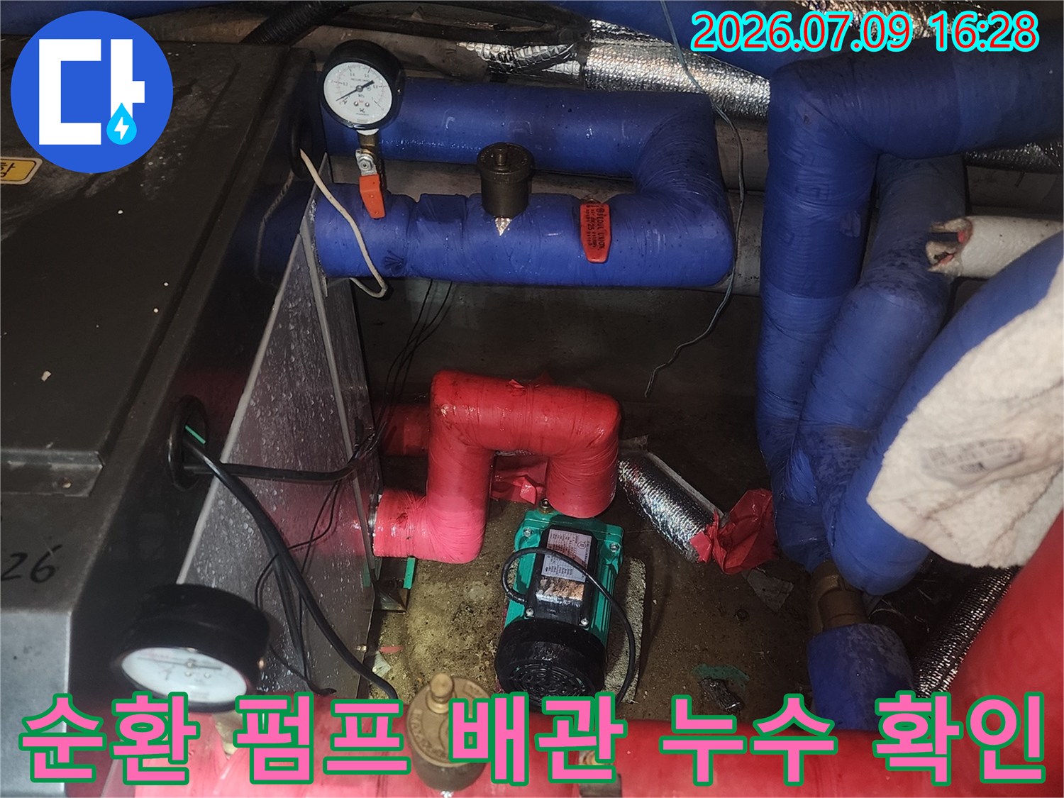 빨간색 보온재로 감싸진 배관과 파란색 배관이 연결된 펌프 부위