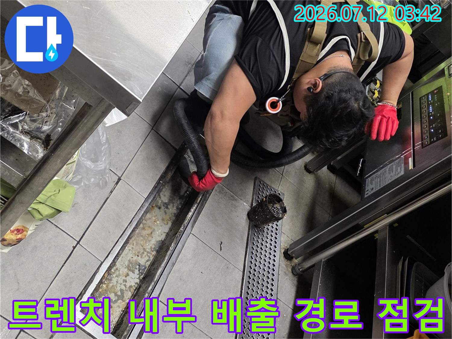 전문가가 주방 트렌치 안의 오염된 슬러지와 배관 상태를 육안으로 검수하는 모습