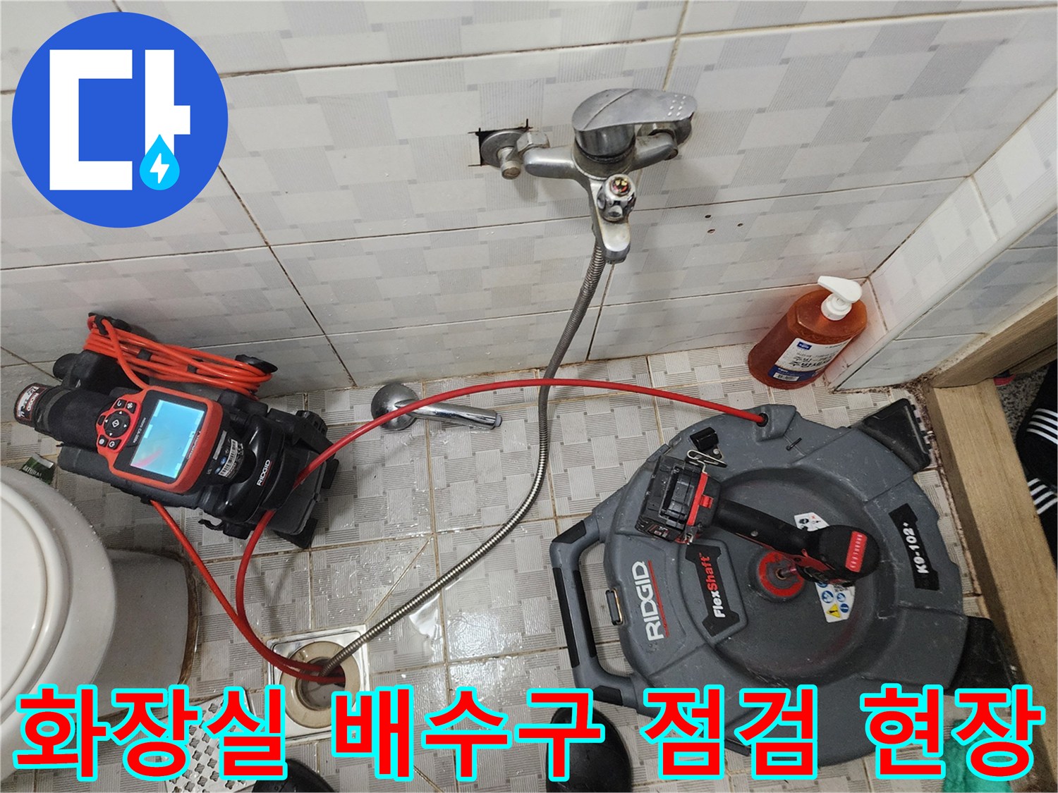화장실 바닥 배수구 주변에 내시경 장비와 공구를 배치한 모습입니다.