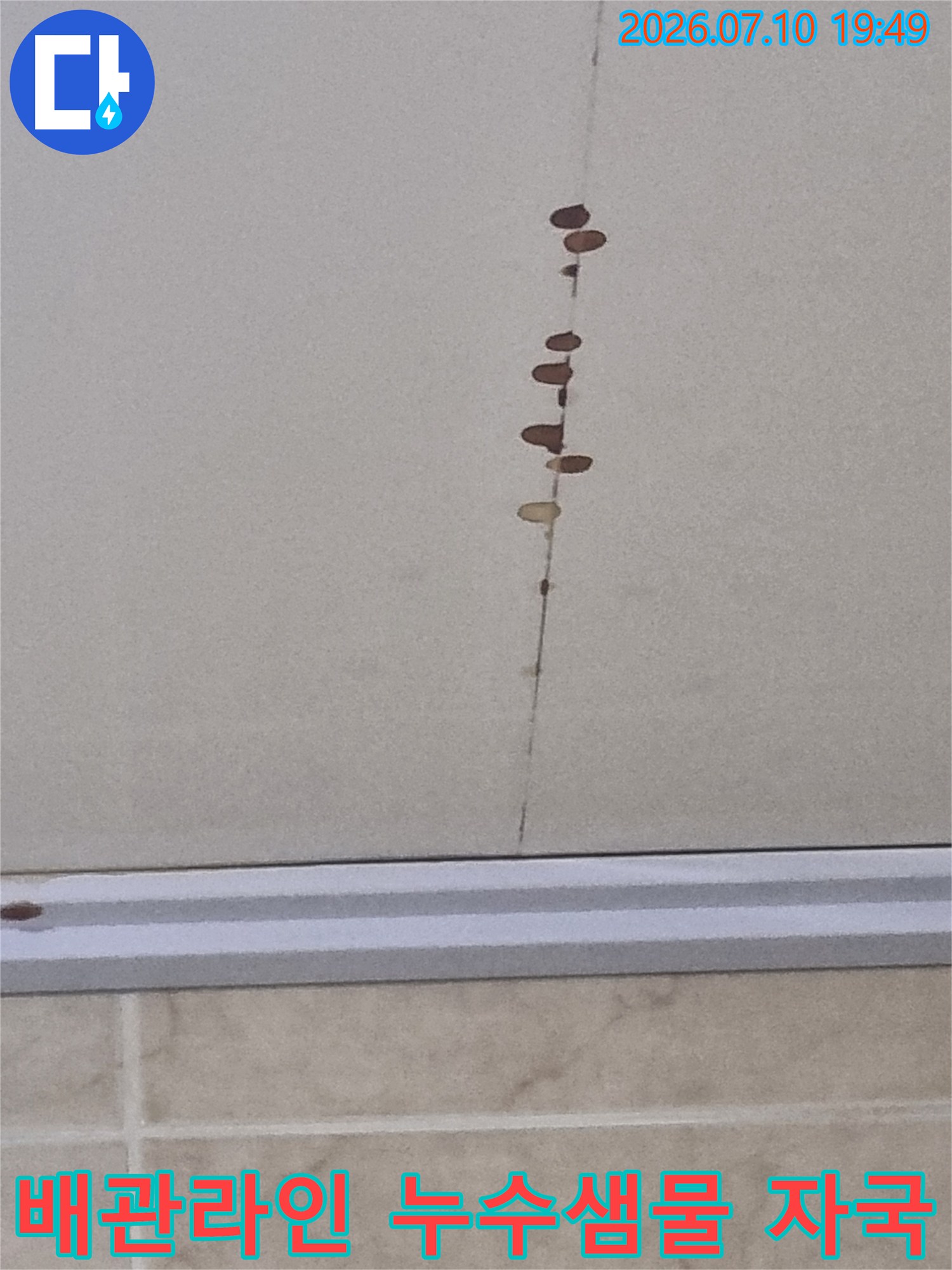 배관을 따라 수직으로 길게 형성된 갈색의 물자국과 오염 부위