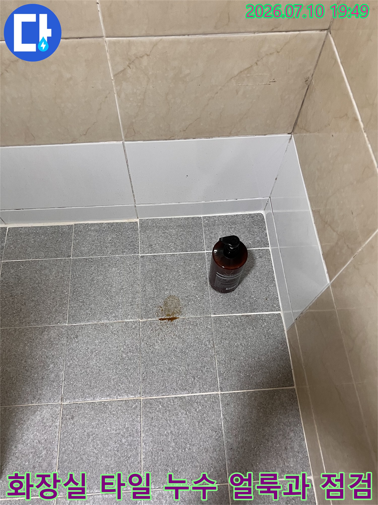 화장실 바닥 타일의 갈색 누수 흔적과 진단 장비가 배치된 모습