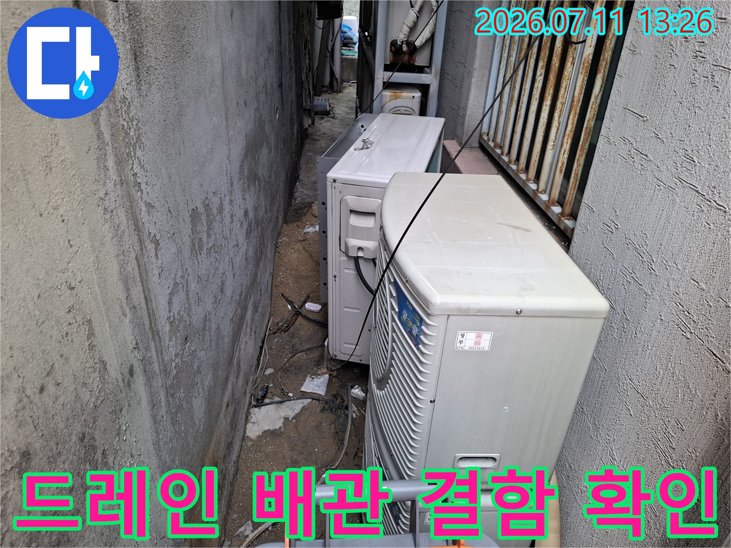 에어컨 실외기 공간 내 노출된 배수라인과 연결 지점의 상태를 면밀히 살피는 모습입니다.