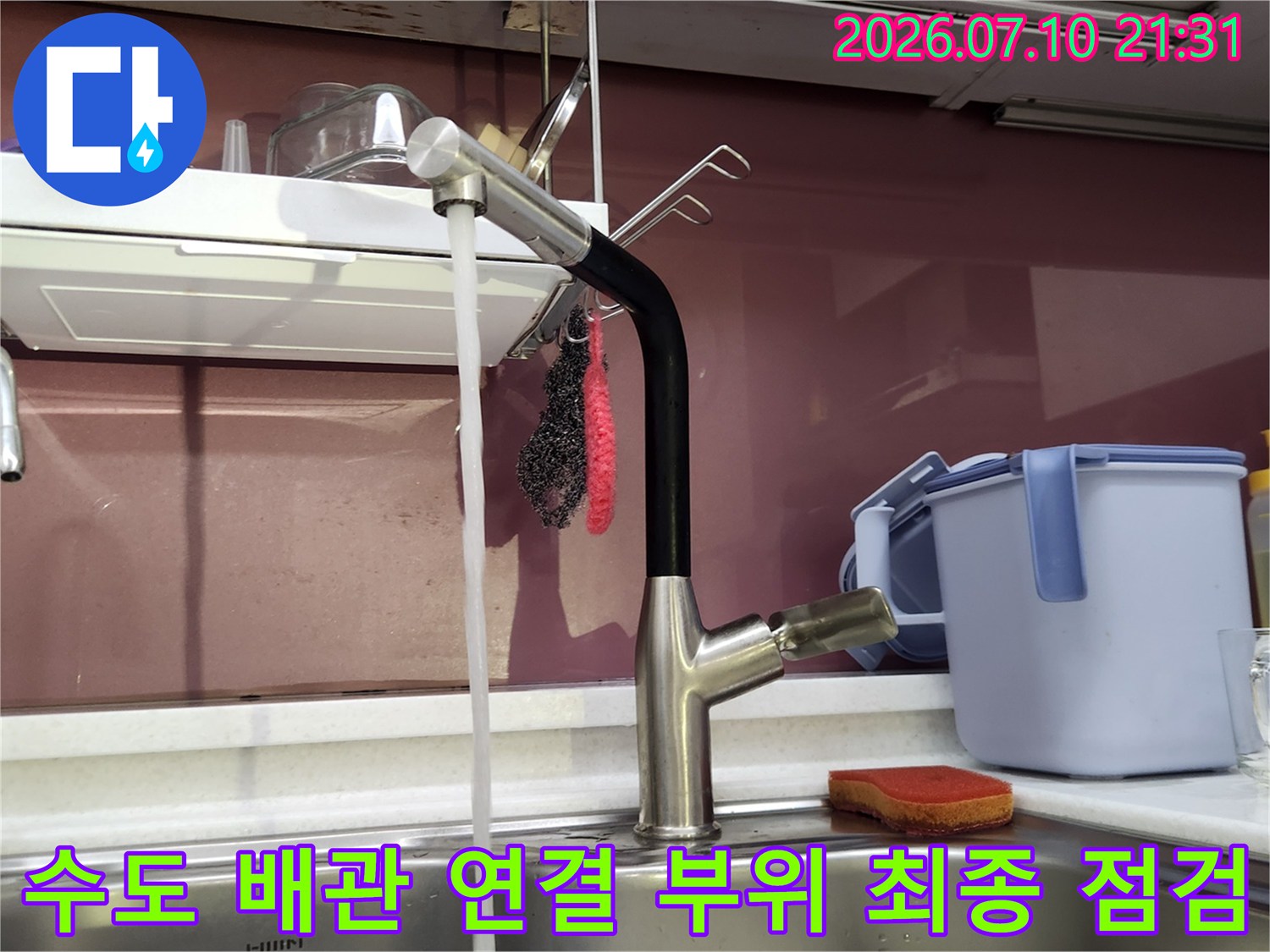 싱크대 아래쪽 온수 호스와 밸브가 견고하게 체결되었는지 확인하는 장면