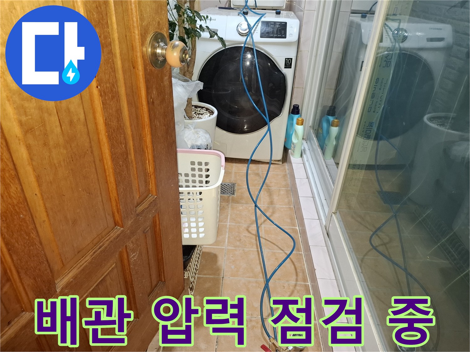 세탁실 바닥 타일 위에 놓인 파란색 호스와 측정 장비