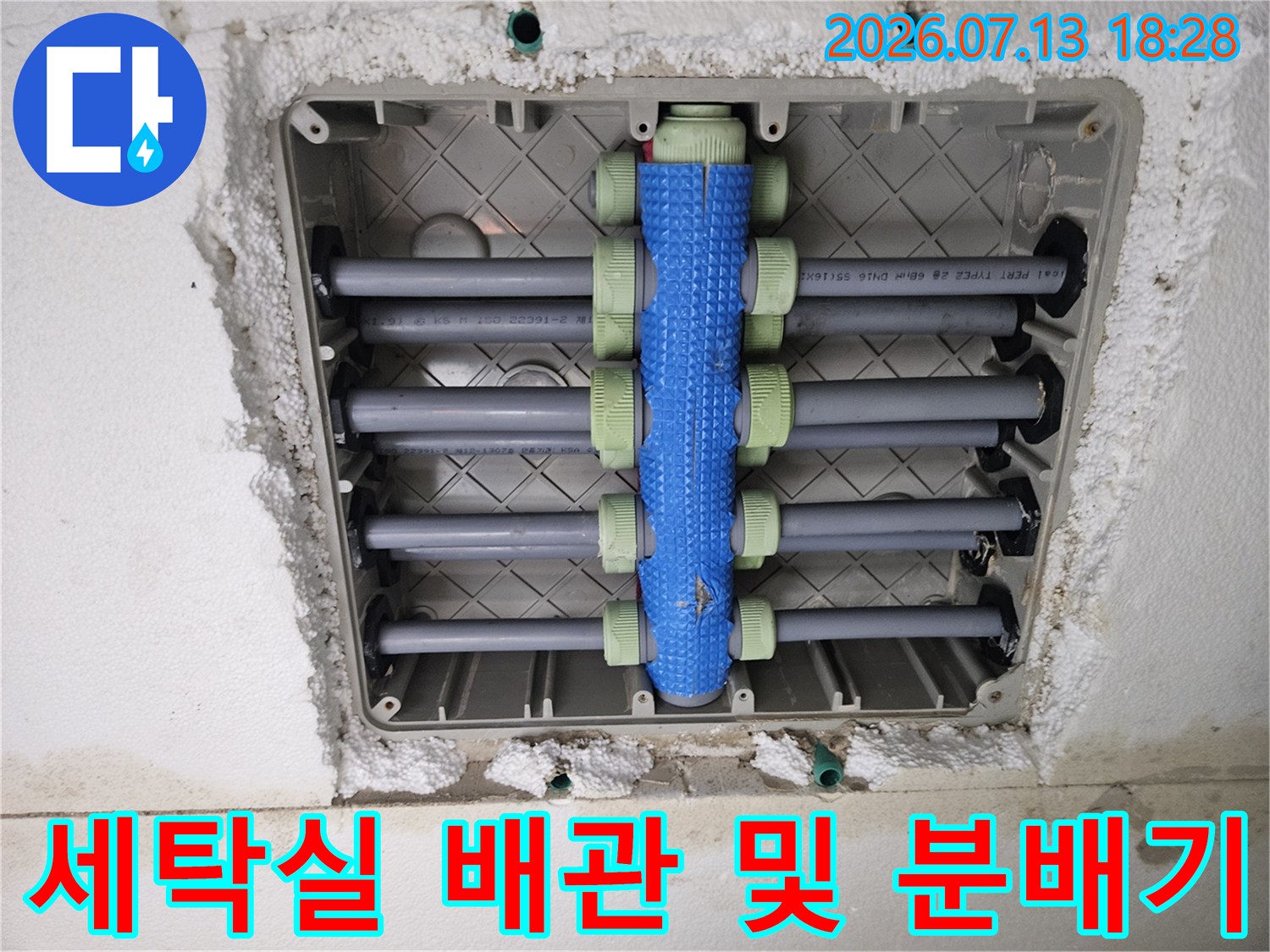파란색 밸브가 달린 세탁실용 분배기와 연결된 노출형 배관들