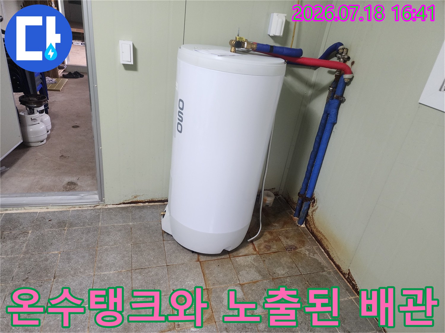 흰색 온수 탱크 옆에 연결된 빨간색과 파란색의 노출 배관 시스템