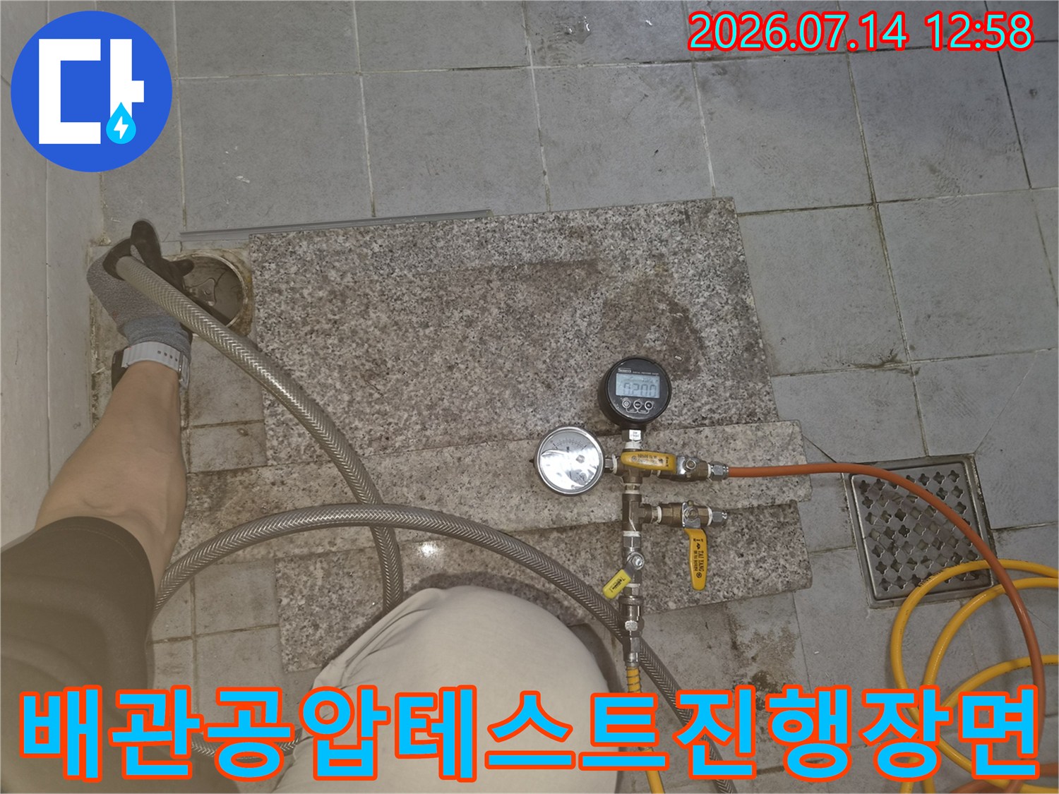 작업자가 장갑을 착용하고 배관에 연결된 압력 측정 장치를 세팅한 모습