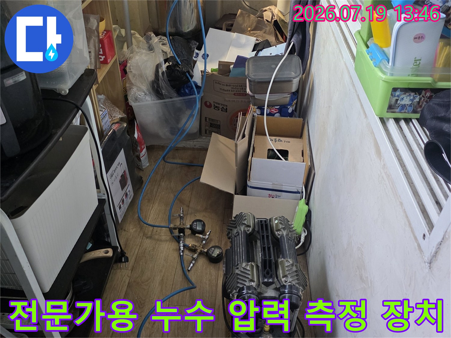 파란색 호스가 연결된 콤프레샤 형태의 누수 탐지 장비가 바닥에 설치된 상태