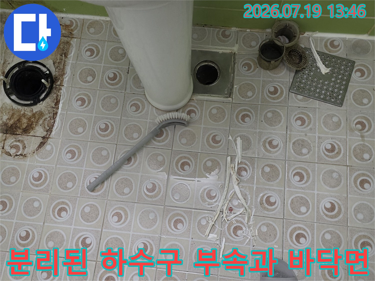 화장실-바닥-타일-위로-드러난-하수관-입구와-플라스틱-부품들