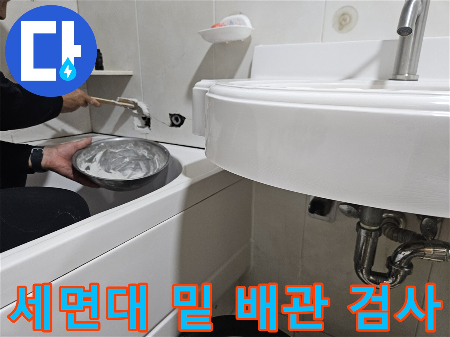 세면대 아래쪽 배관 연결 부위의 누수 여부를 확인하고 있습니다.