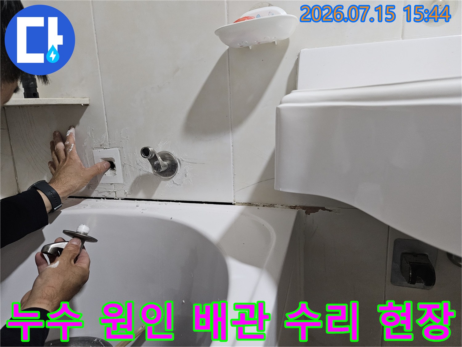 세면대 하단에 위치한 배관 연결부를 손으로 점검하는 장면