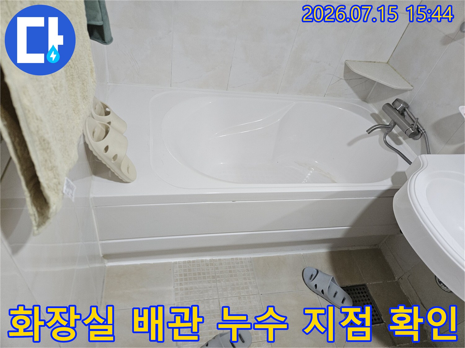 세면대와 욕조 사이 공간의 배관 상태를 정밀하게 점검하는 장면