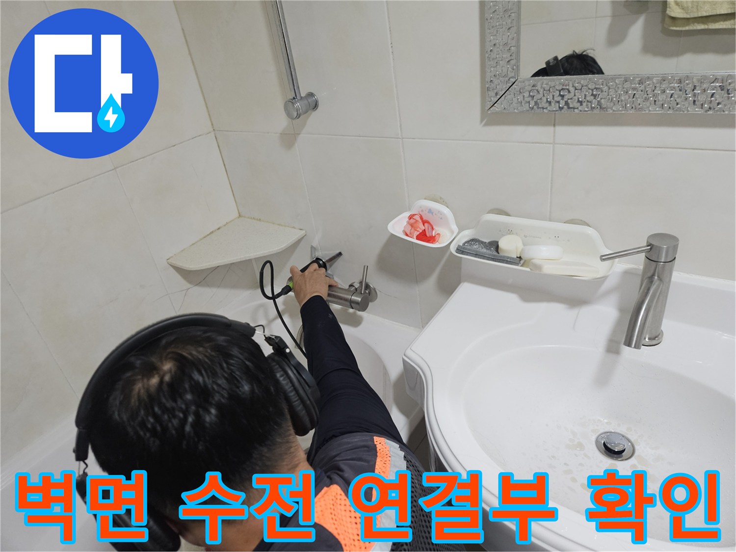 욕실 벽면에 설치된 수도 부속의 누수 여부를 점검하는 모습입니다.
