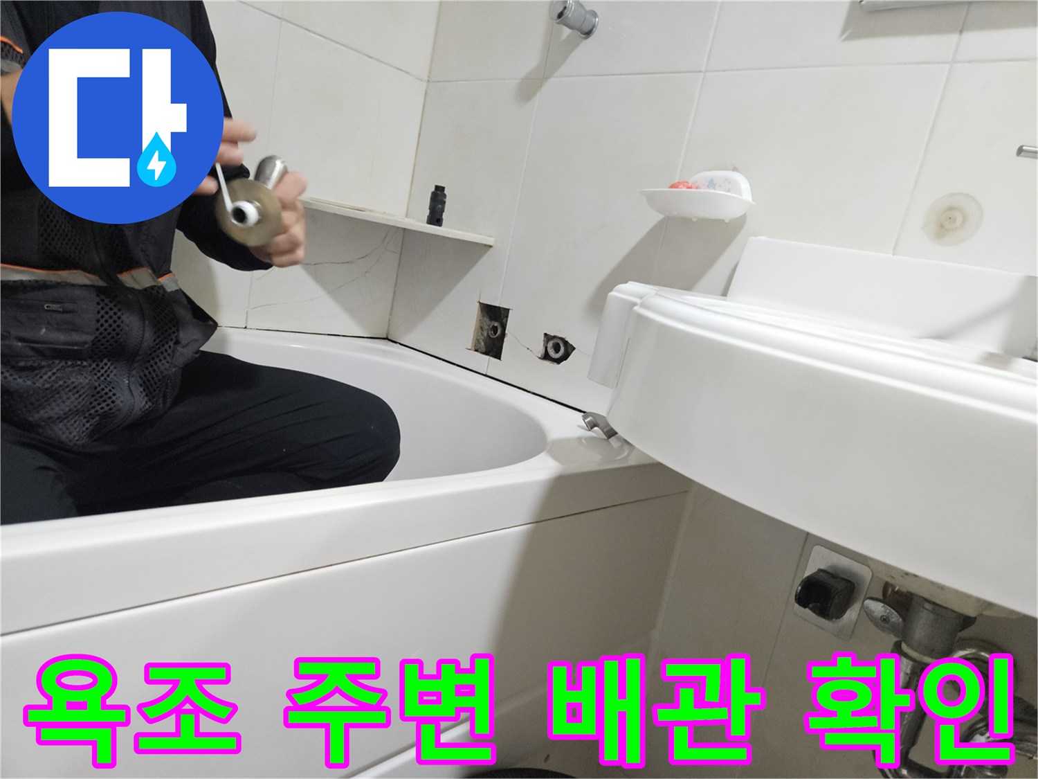 욕조 하부와 벽면 타일 사이의 배관 상태를 점생하는 모습