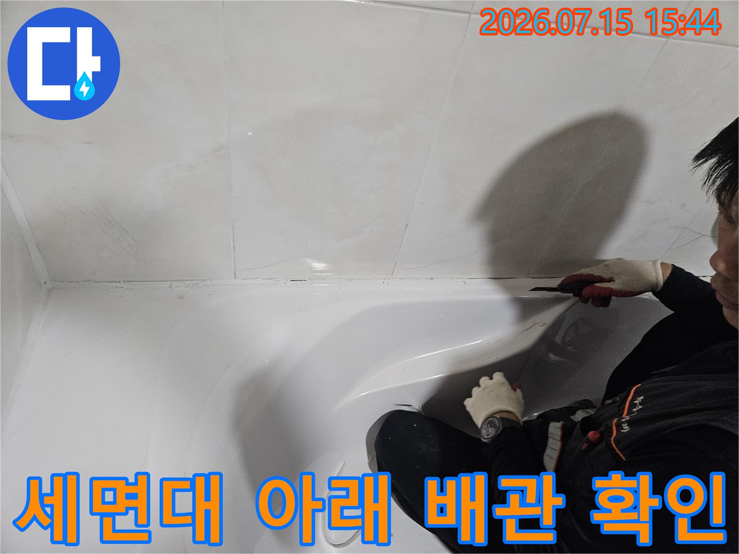 장갑을 끼고 세면대 하부의 젖은 부위를 조사하는 장면